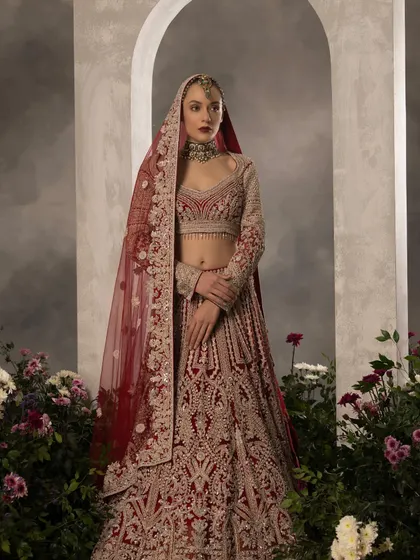 A full-length view of a bride in a magnificent red and gold embroidered lehenga. I styled this with a double dupatta for added regality, a technique I often use to create a more layered and traditional silhouette for the wedding ceremony.