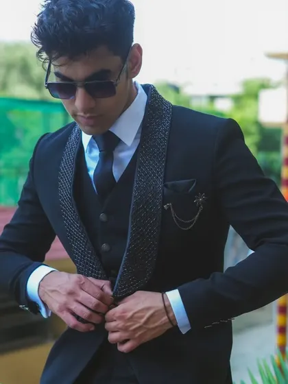 A model adjusting his black designer suit, showing it's made for movement and comfort.