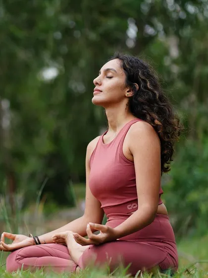 Seated in meditation in a lush green park. This image is paired with reflections on creating healthy morning and night routines to achieve your goals and live a more peaceful life.