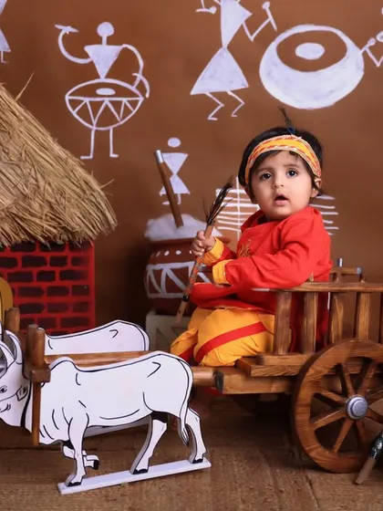 A single portrait of a child in our bullock cart, holding a prop. The simple, direct gaze makes for a powerful and charming Janmashtami photograph.