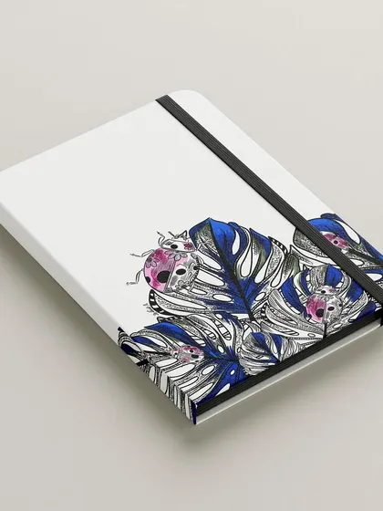 My ladybug illustration on the cover of a notebook. The design combines detailed black and white leaves with pops of colour on the ladybugs, making it a unique and artistic piece of stationery.
