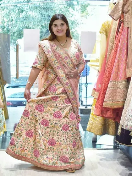 A full-length view of the client admiring the fit of the beautiful floral lehenga. You can try on as many outfits as you like to find your perfect match.