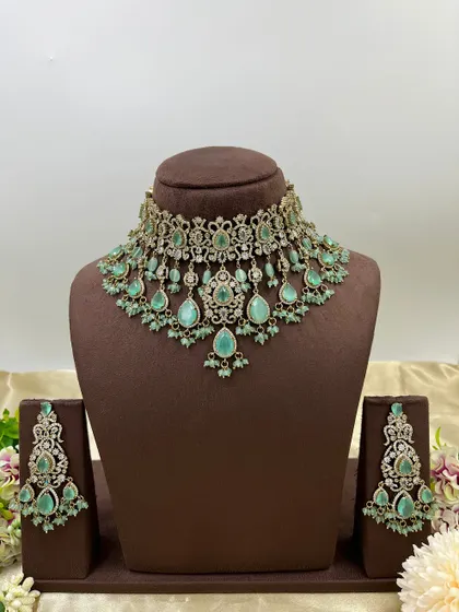 A heavy bridal choker set in a stunning emerald green. This design features multiple layers of stones and bead droppings, complete with matching oversized earrings, making it a comprehensive offering for your bridal customers.