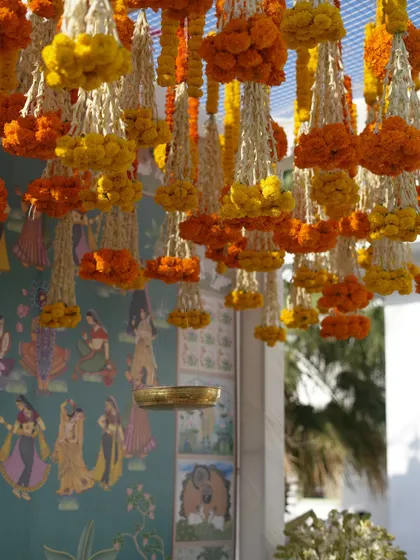Looking up at the ceiling, where strings of marigolds and tuberose hang, creating a fragrant and beautiful canopy.