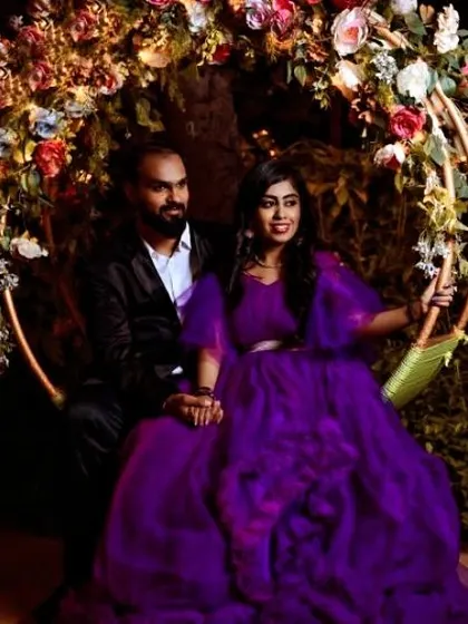 A picture-perfect couple enjoying a quiet moment on a floral swing, her in a beautiful purple ruffle gown.