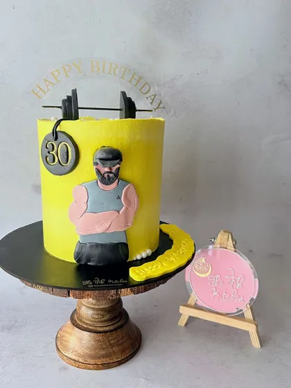 A cake for a fitness enthusiast turning 30. It features a handmade fondant caricature of the birthday boy, complete with a barbell and weight plate.