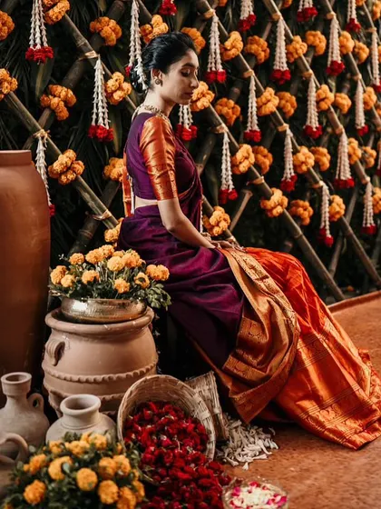 A bride poses against a traditional backdrop of earthen pots and marigold flowers.