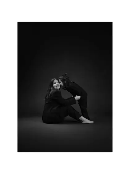 A whispered secret between mother and daughter. The intimacy of this moment is heightened by the classic black and white style, making it feel like a precious, frozen memory.