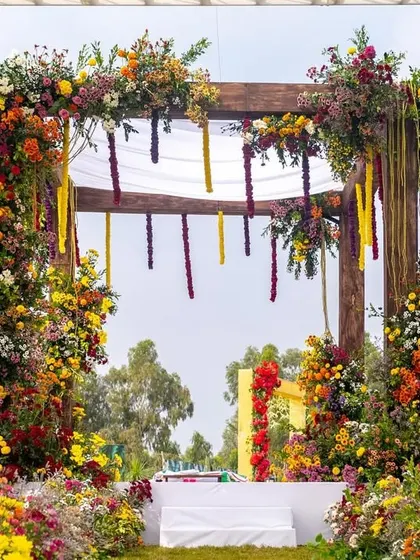 A view of the floral mandap from the guest's perspective, with a pathway lined with colorful blooms leading to the main stage.