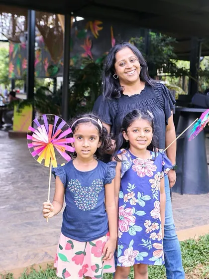 A mother and her two daughters enjoying a day out, with colorful pinwheels in hand.