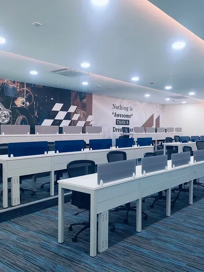 The main auction hall is designed with tiered seating and individual desks to facilitate a focused and comfortable bidding process. A large automotive-themed mural adds a dynamic visual element that reinforces the brand's identity.