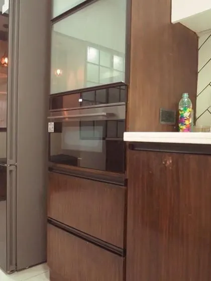 This image highlights the integrated tall unit with a built-in oven, demonstrating how we seamlessly blend appliances into our classic kitchen designs. The wood grain provides a sense of warmth and texture.