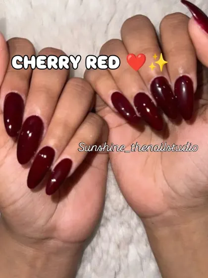 A classic set of long, almond-shaped nails in a glossy cherry red.
