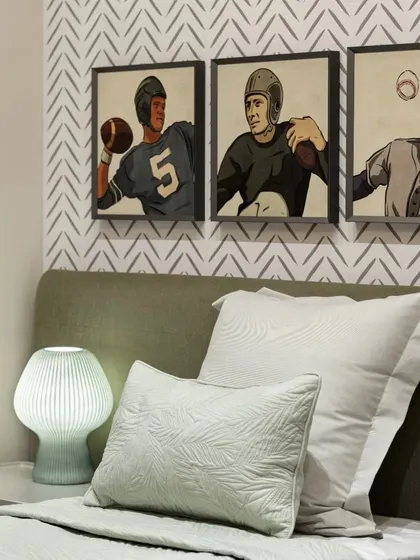 The second bedroom in the Max128 apartment, featuring a geometric wallpaper and sports-themed art for a classic, refined feel.