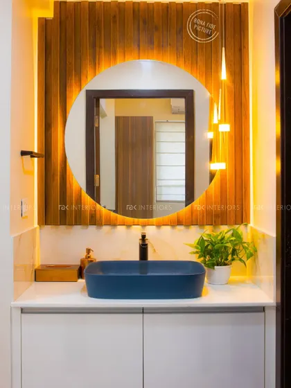 Style statements done right. This well-lit wash counter features a bold blue vessel sink, a backlit round mirror, and a wooden reeded panel, creating a modern and luxurious feel.