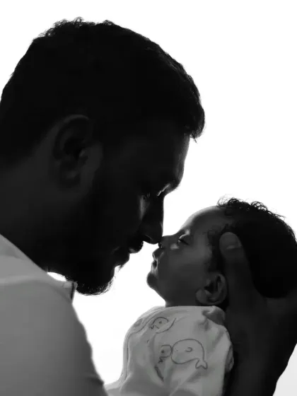 A powerful black and white silhouette of a father holding his newborn, capturing a moment of quiet connection.