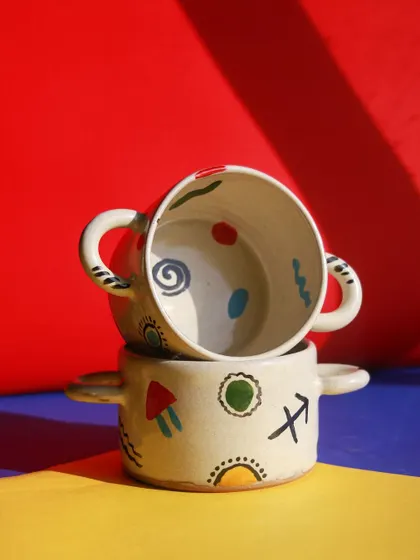 Two stacked bowls with handles from the 'Playful Mornings' collection, showcasing their bright, playful patterns and functional design.