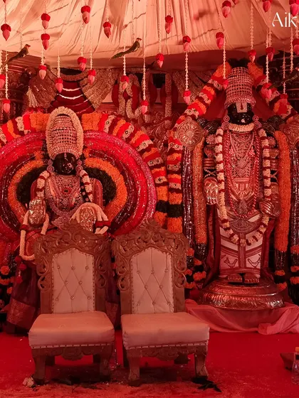 A closer view of the deity-centric wedding stage. The ornate thrones for the bride and groom are placed directly before the beautifully decorated idols, symbolizing a marriage blessed by the divine.