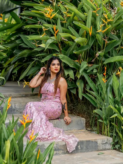 A model seated in the pink sequined gown, showcasing its elegant drape and shimmer. I focus on using fabrics that not only look good but also feel luxurious.