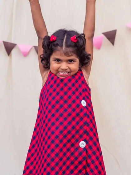 Full of energy in this red and navy checkered dress. The wrap-style front with large white buttons is a fun, modern detail on a classic pattern.
