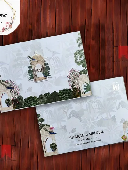 This elegant white and green Pichwai invitation features delicate bird and garden motifs, complete with a personalized monogram for a bespoke touch.