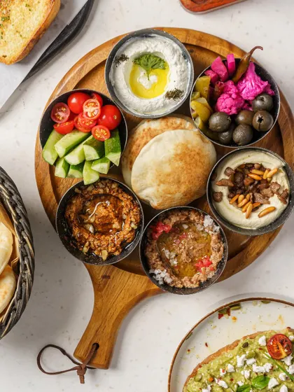 A Middle Eastern mezze platter, shot from above to display the variety of dips and fresh ingredients. This is a classic food photography style for menus and promotional materials.