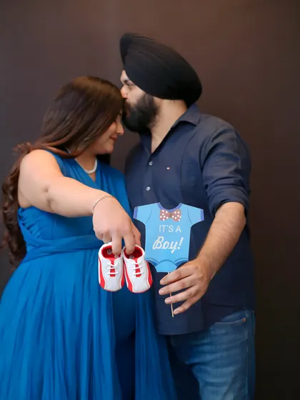 It's a boy! This photo shows how we can incorporate fun props to announce your baby's gender during your maternity shoot. The tiny shoes and sign add a personal and playful touch to the memory.