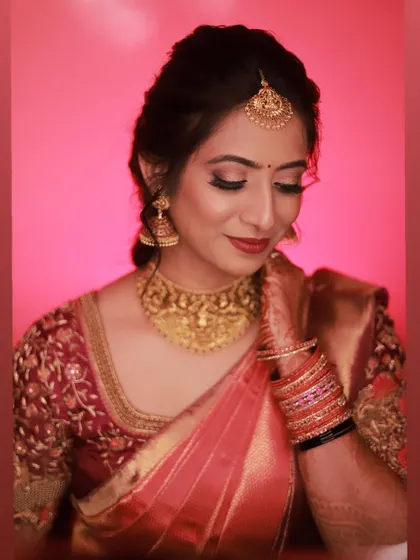 A classic bridal portrait with a vibrant background. The makeup features a soft smokey eye and a reddish-pink lip, creating a timeless and beautiful look.