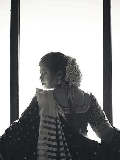 A beautiful and contemplative black and white shot of a bride looking out a window from behind. The bright light creates a strong silhouette, evoking a sense of looking towards the future.