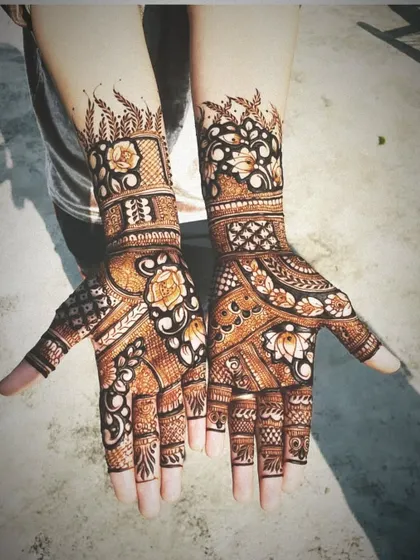 A stunning example of full-hand Indo-Arabic mehndi. The design features a mix of floral patterns, jaali work, and bold leafy vines, creating a balanced and breathtaking look for both hands.