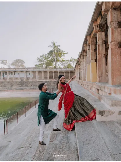 A playful moment on the steps of a temple tank, with the groom helping his bride-to-be.