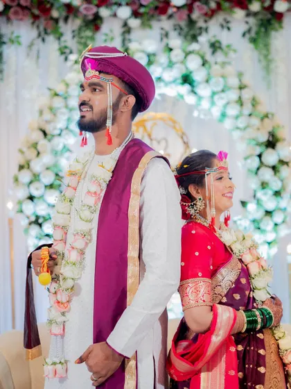 A stylish back-to-back portrait of the bride and groom in their vibrant Maharashtrian wedding attire.