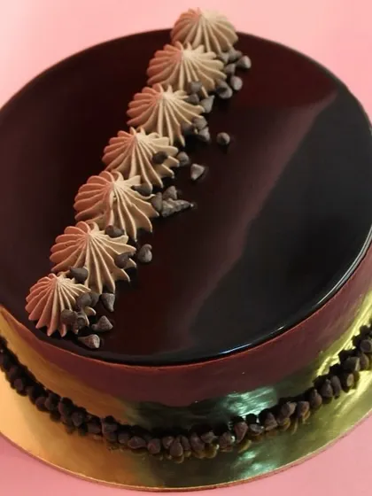 Our best-selling eggless chocolate cake with a simple, elegant mirror glaze, accented with piped chocolate cream and chocolate chips.