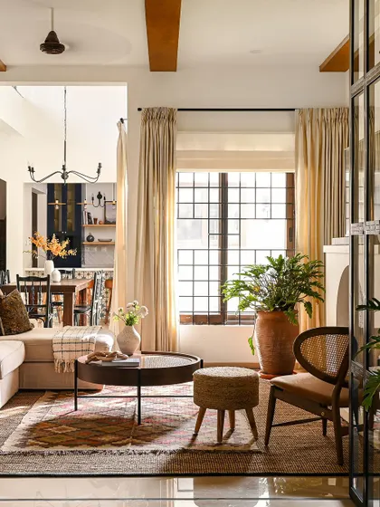 This angle of the living room shows the interplay of light and texture. The natural light from the large window highlights the different materials in the room, from the jute rug and rattan stool to the soft linen sofa and terracotta planter.
