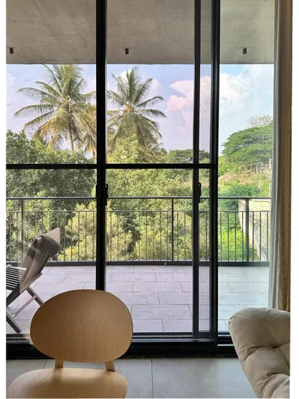 The view from inside looking out to the balcony. The large glass doors frame the lush greenery, making it feel like a part of the interior decor.