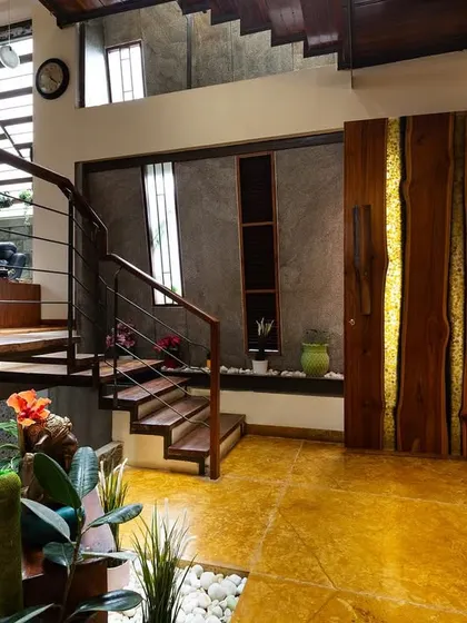Details matter in creating a warm and inviting entryway. Here, a custom wooden door with a natural live edge complements the polished yellow oxide floor and an indoor planter, setting a tone of earthy elegance from the moment you step inside.