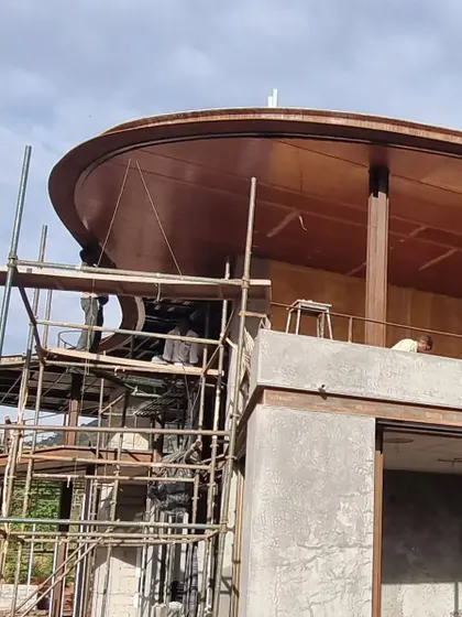 The curved steel and wood canopy of 'the hat' being meticulously assembled on site. This element is a defining feature of the design, and its construction required great skill and craftsmanship.
