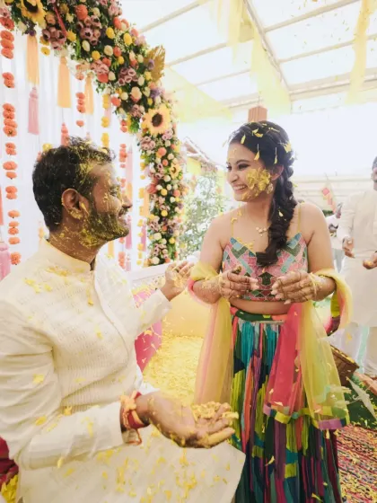 Drenched in love and turmeric. This candid shot captures the playful spirit of the Haldi ceremony, set against a beautiful floral arch.