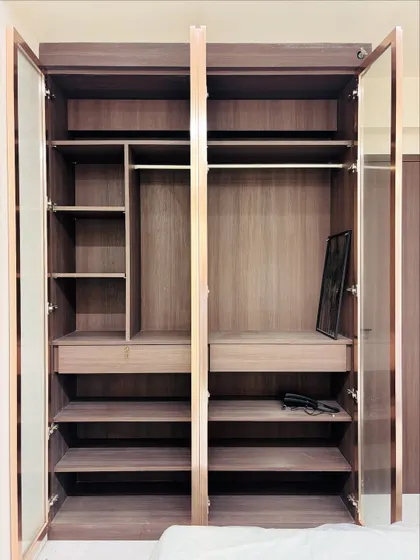 The interior of the glass-door wardrobe, showing the customisable layout with hanging rods, shelves, and drawers.