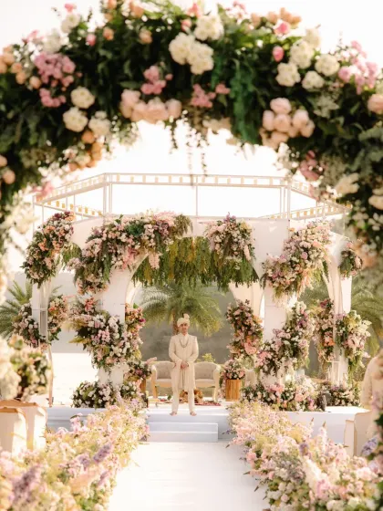 The groom awaits his bride at the 'Garden of Love' themed mandap in Udaipur. The structure is designed with arched frames and asymmetrical floral arrangements to create a modern yet romantic look.