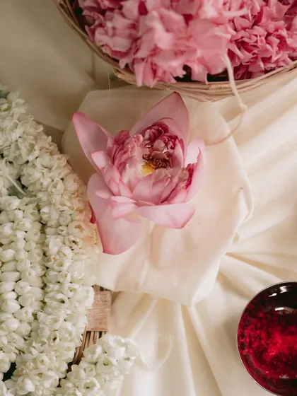 A single pink lotus, a symbol of purity and beauty, rests on soft white fabric. It's these small, thoughtful details that elevate the decor and add deeper meaning to the celebration.