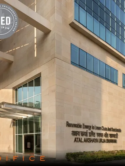 The impressive stone facade and entrance of the Atal Akshaya Urja Bhawan, a LEED Platinum certified project. The engraved name signifies its role as a key center for renewable energy in India.