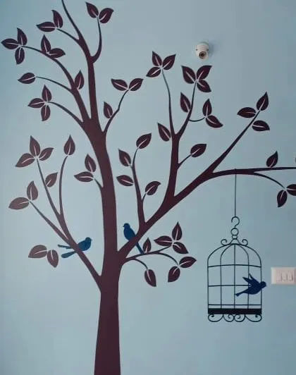 An identical view of the tree and birdcage stencil, perfect for a living room or bedroom wall to bring a touch of nature indoors.