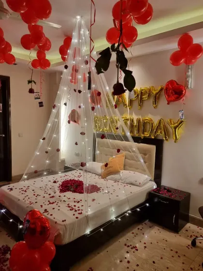The bed adorned with a fairy light canopy, scattered rose petals, and hanging roses.