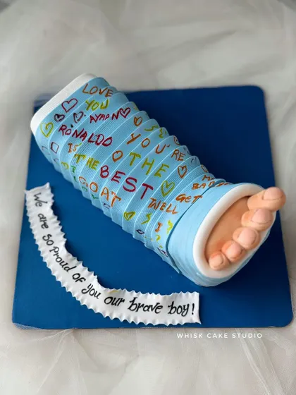 A unique "get well soon" cake shaped like a cast on a broken leg. The cast is covered in encouraging, handwritten messages, making for a truly personal gift.
