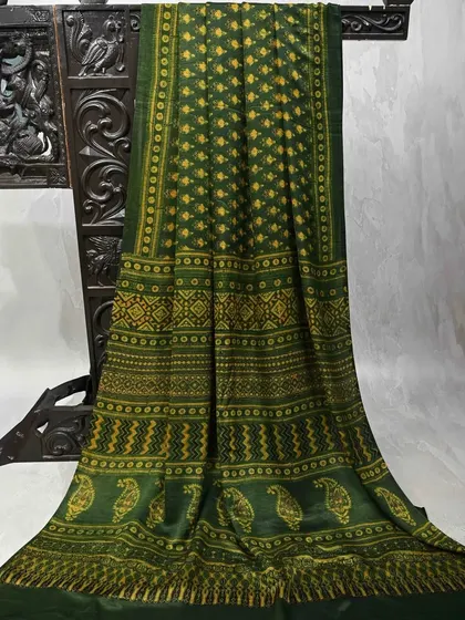 A deep green saree with traditional block prints. The paisley and geometric patterns make it a classic and elegant piece.