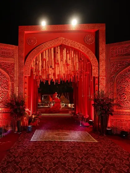 The entrance to a celebration should feel like stepping into another world. I used intricately carved crimson panels and a dramatic arch to create a grand, regal welcome for this wedding.