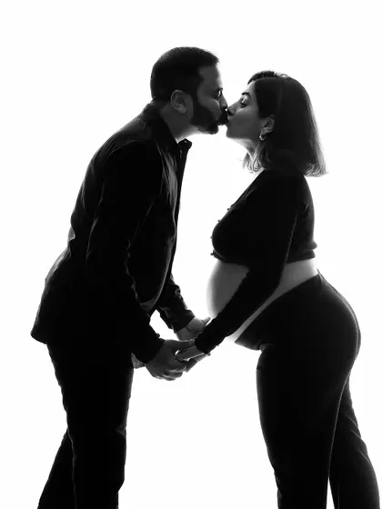 The same intimate moment, presented in timeless black and white. This artistic choice emphasizes the emotion and connection between the couple, creating a powerful and classic maternity photograph.