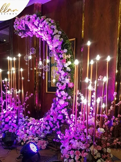 A unique photo opportunity I designed for a Sangeet. A crescent moon-shaped floral installation with hanging crystal drops and candle-lit pillars creates a magical and romantic spot.