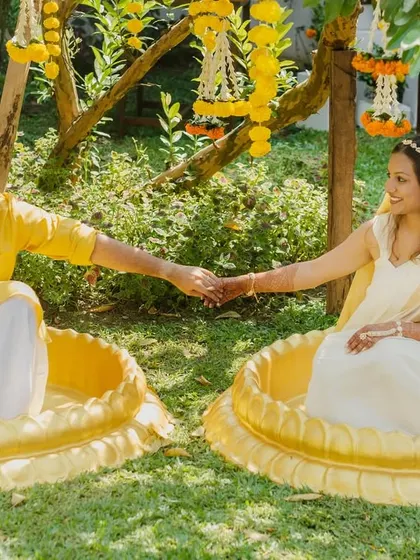 The couple holds hands while seated in their haldi urns, a playful and unique shot from their destination wedding.